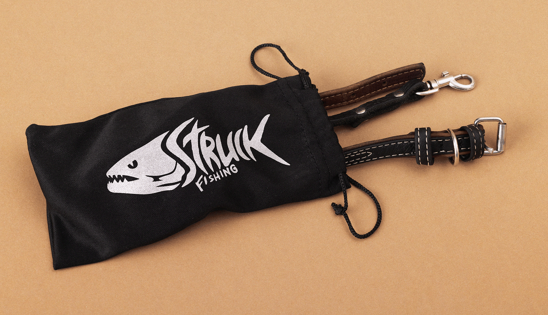 Bolsa de acessórios de pesca com logotipo Struck Fishing bordado, sobre fundo de cortiça